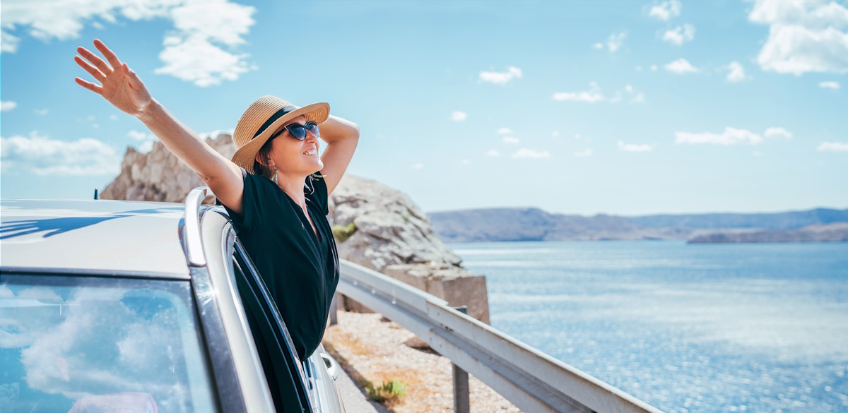 Frau mit Auto am Meer