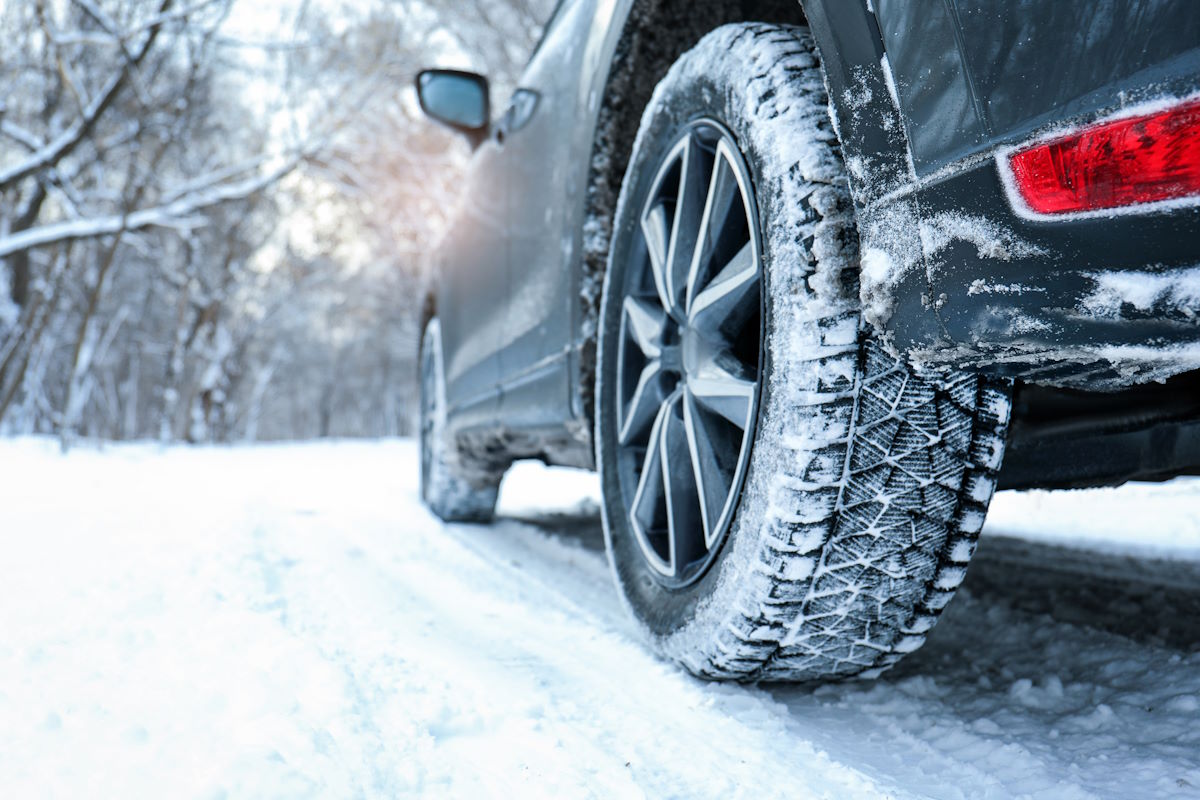 Auto mit Winterreifen in winterlicher Landschaft